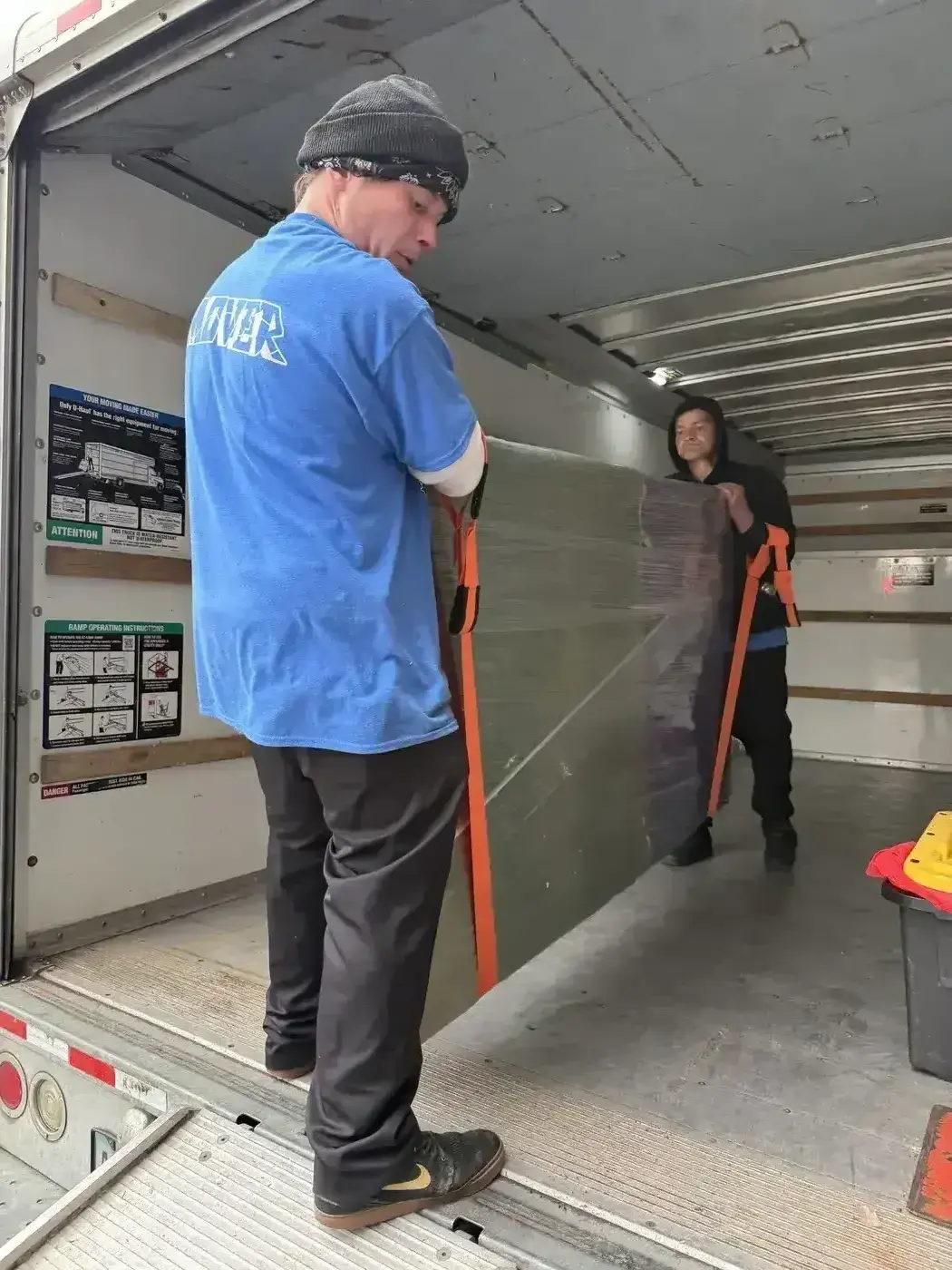 Movers unloading items with straps